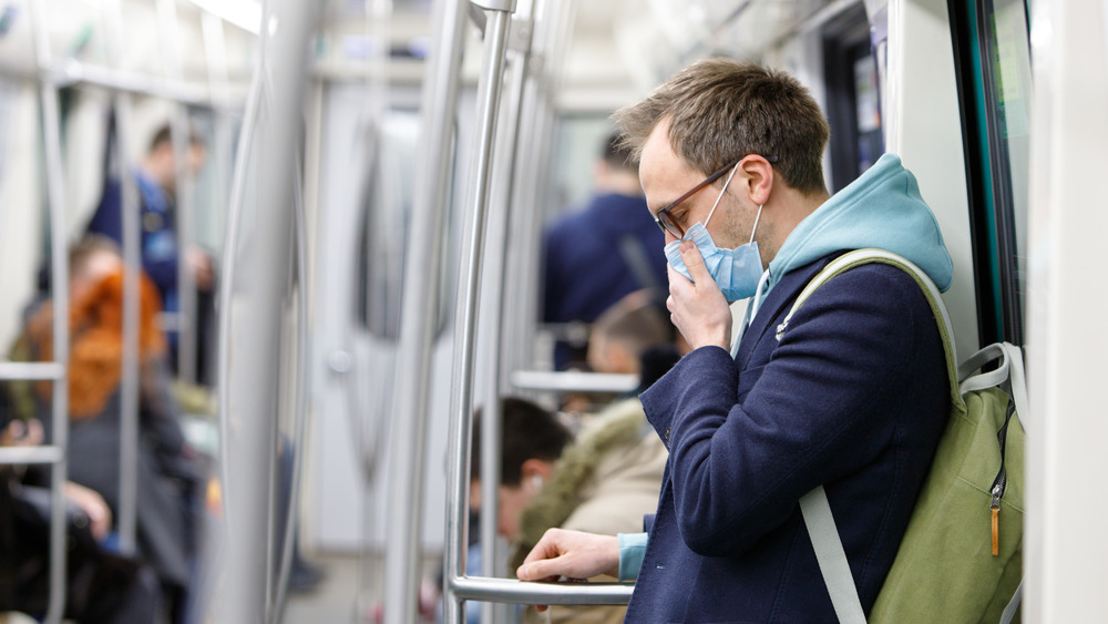 Masked man coughing on transit