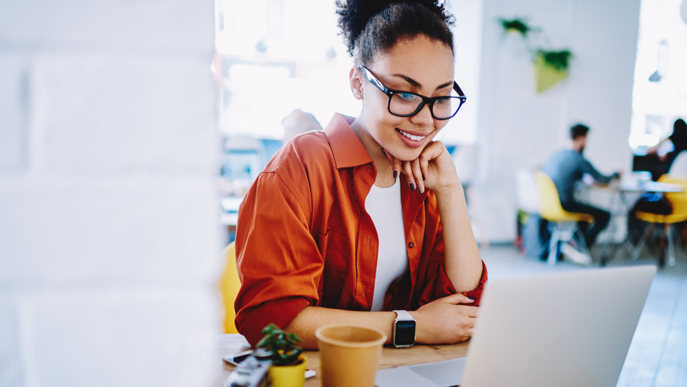 Woman sitting and looking at laptop, smiling