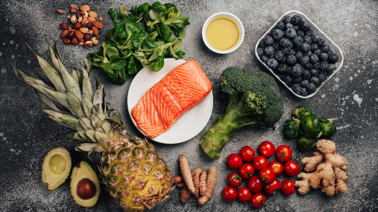 Variety of fruits, vegetables, nuts, and herbs around a plate of salmon