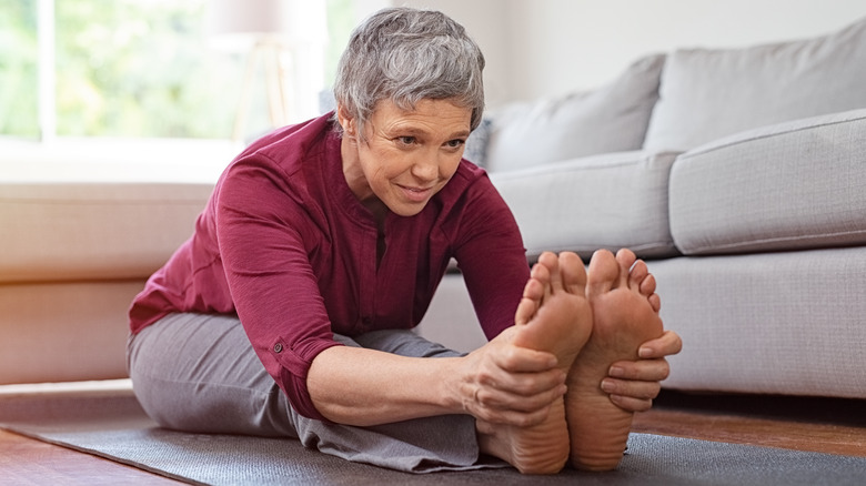 Older woman stretching on yoga mat