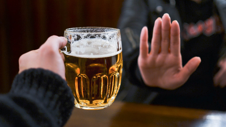 Hand refusing an offered glass of beer