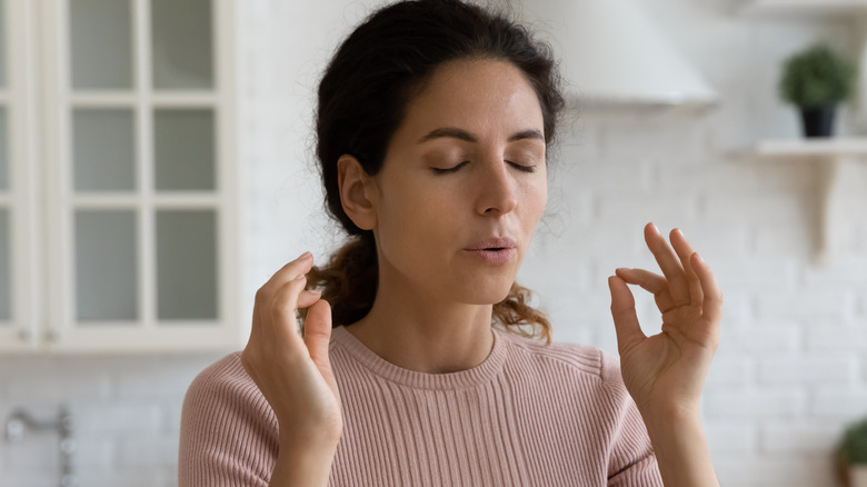 Stressed woman sitting in kitchen breathes out slowly