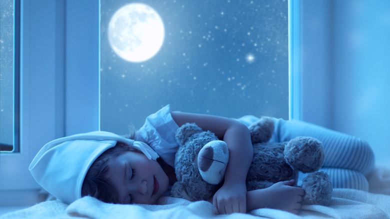 child sleeping under a full moon