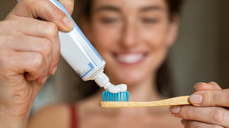 woman putting toothpaste on toothbrush