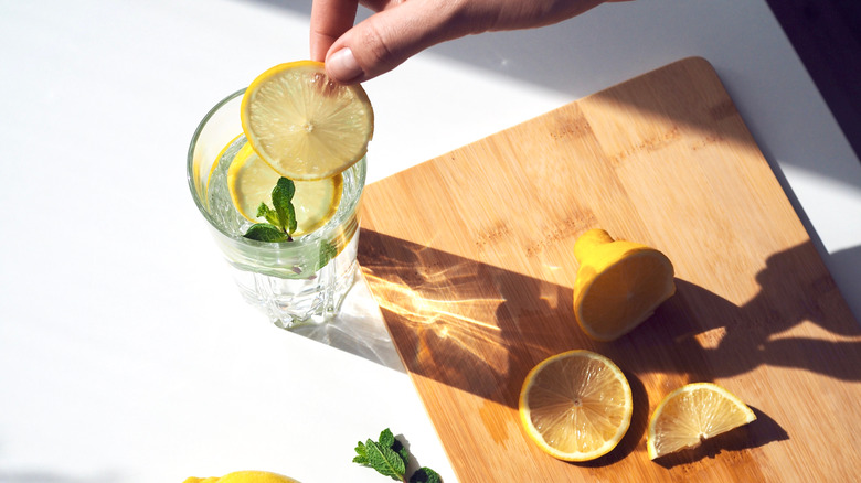 Person cutting lemons into water