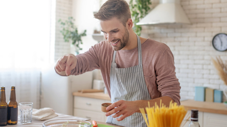 A man adding salt to his glass salad bowl