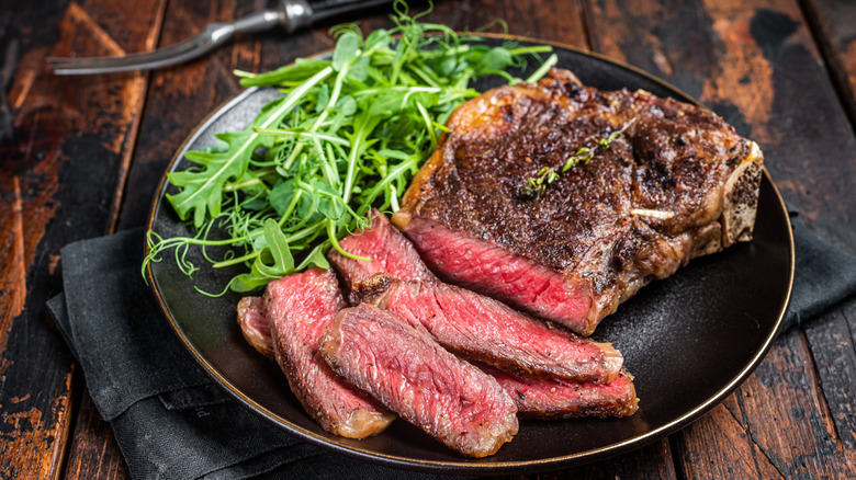 A plate of meat with greens for garnish