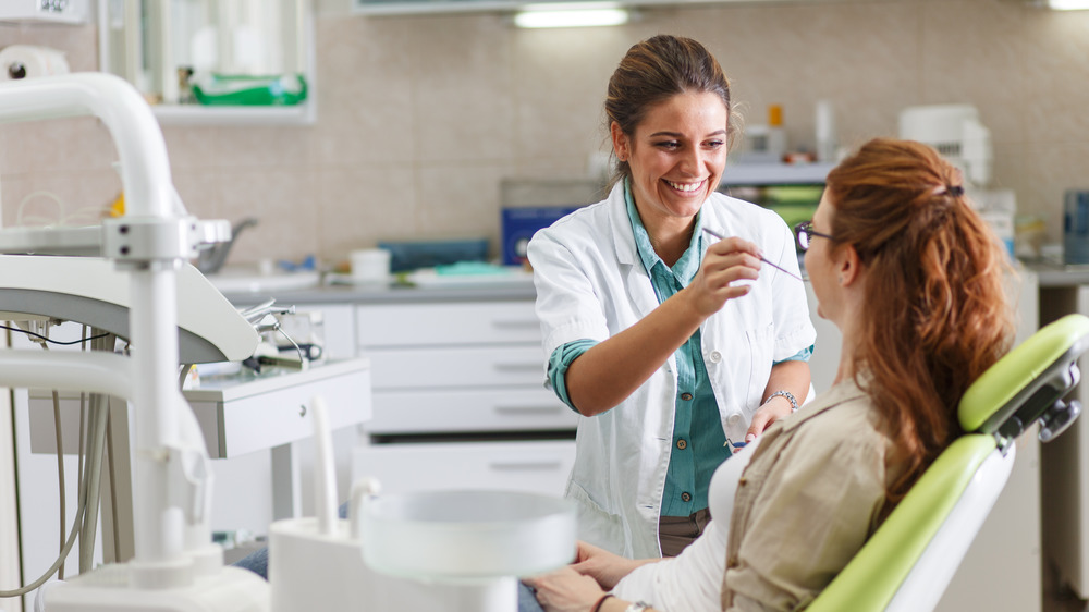 woman in dentist chair talking to female dentist
