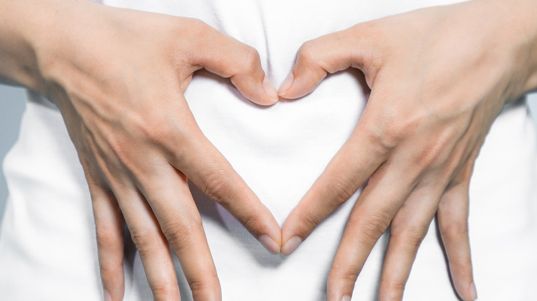 woman forming heart sign on stomach