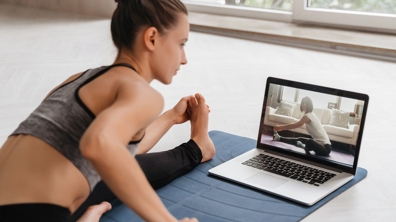 woman watching video on yoga mat