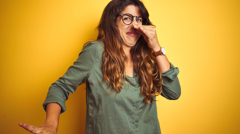 woman plugs nose at bad smell