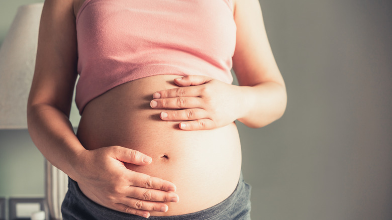 pregnant woman puts hand over bump