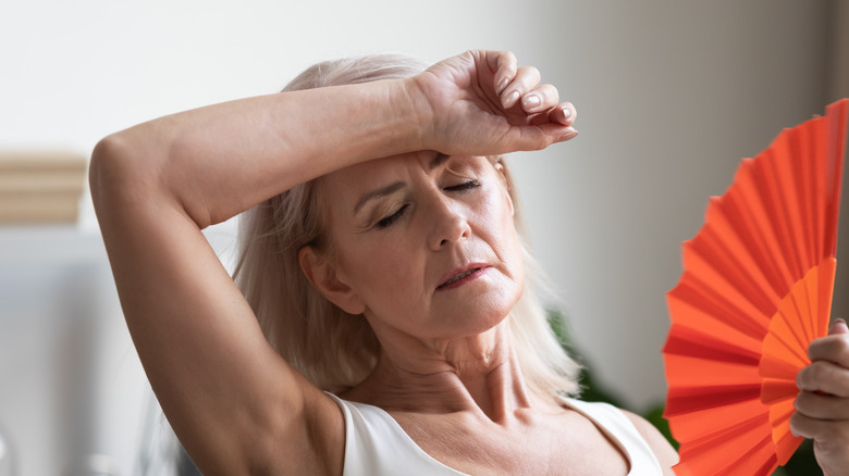 middle aged woman fanning herself having hot flash