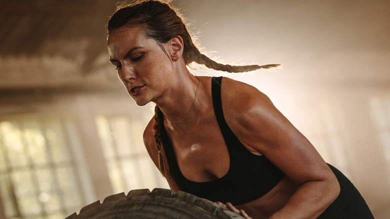 strong woman at gym pushing large tire