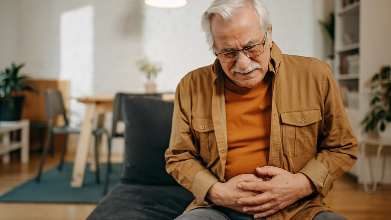 older man holding his gut in pain