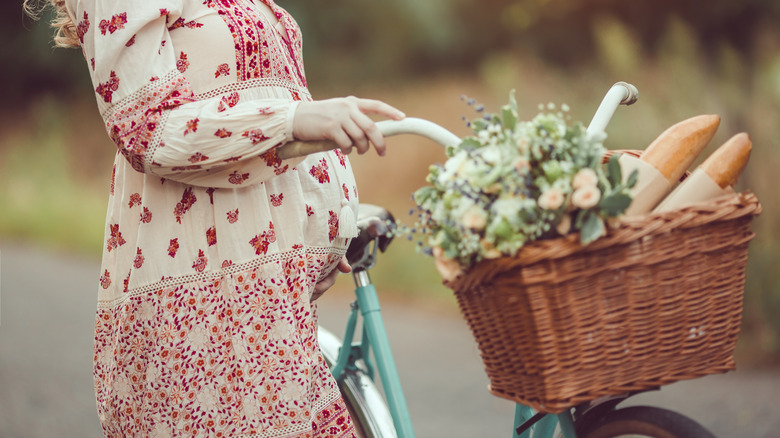 Pregnant woman walking bicycle with bread in the basket