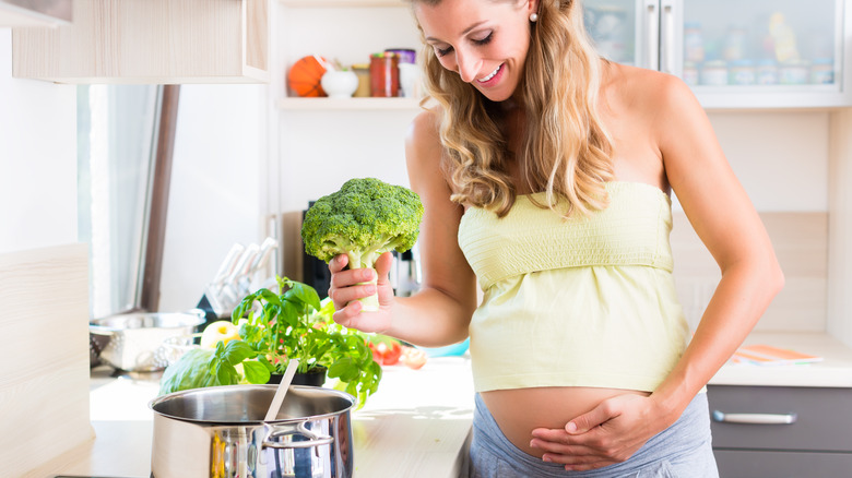 pregnant woman holding broccoli