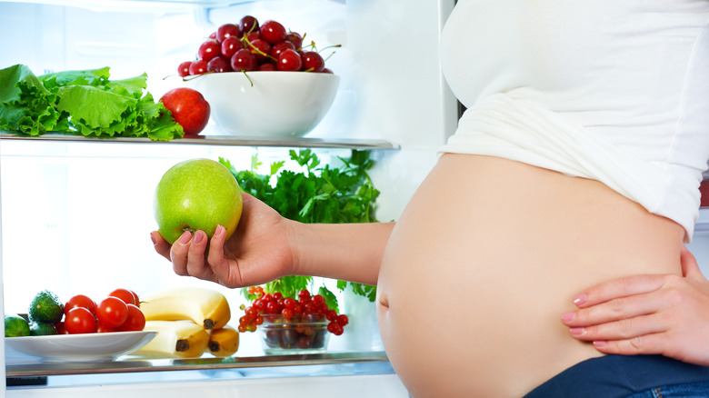 pregnant woman with fridge full of fruit