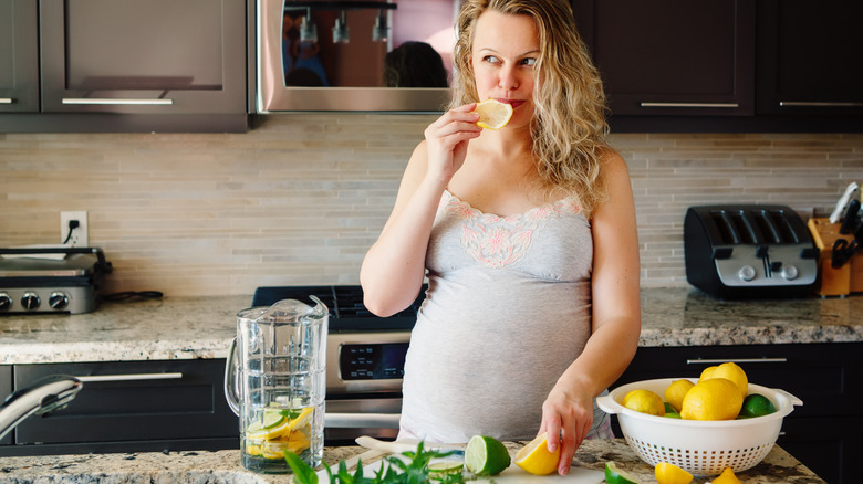 pregnant woman sucking a slice of lemon