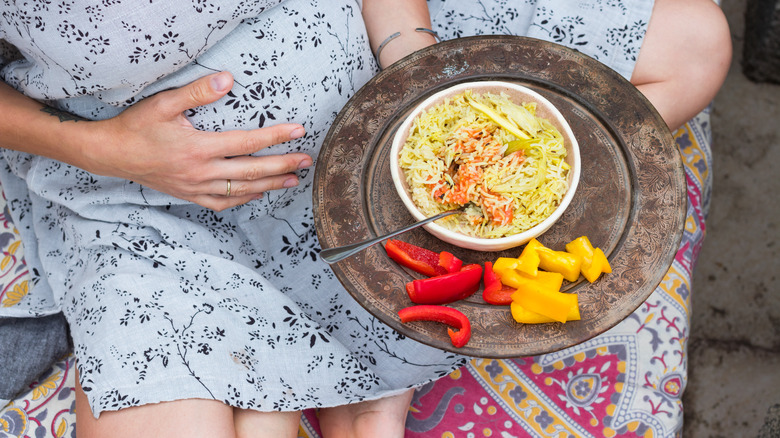 pregnant woman holding a bowl of rice