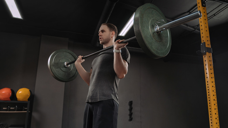 A man performs an overhead press at the gym