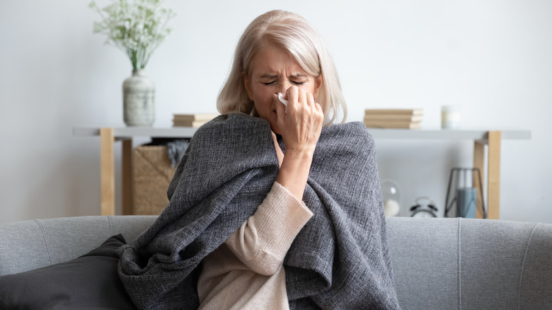 woman sneezing on sofa