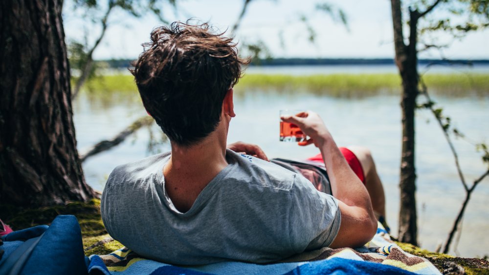 Man relaxing with whiskey by lake