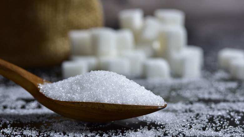 spoon of sugar with sugar cubes in the background