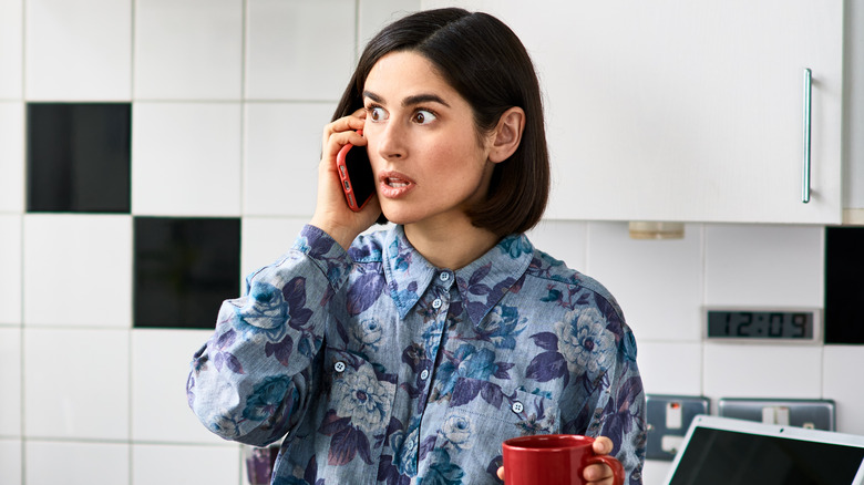 woman surprised on phone in kitchen