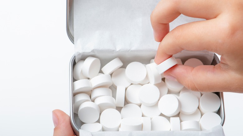 man's hand picking mints from container