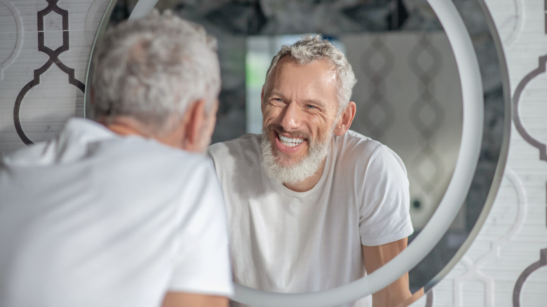 Older man smiling in mirror