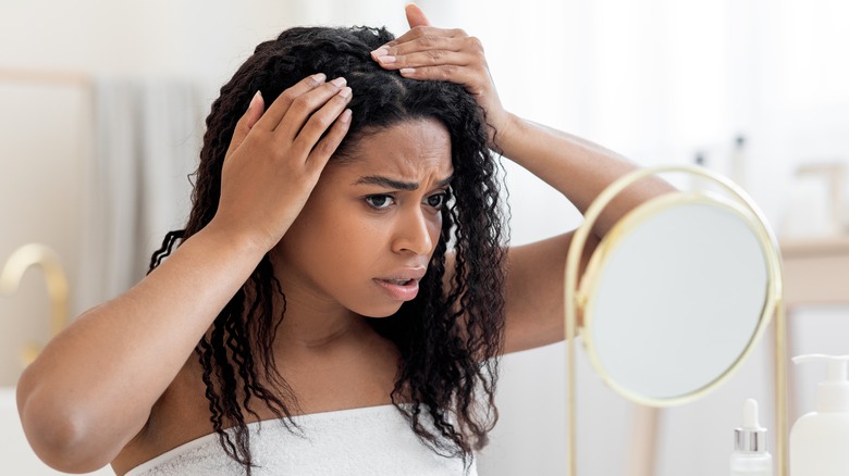 Woman examining scalp in mirror