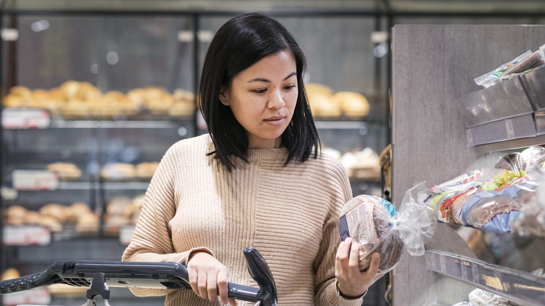 woman reading bread label on loaf at store