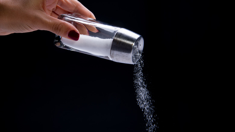 woman's hand pouring salt out of shaker