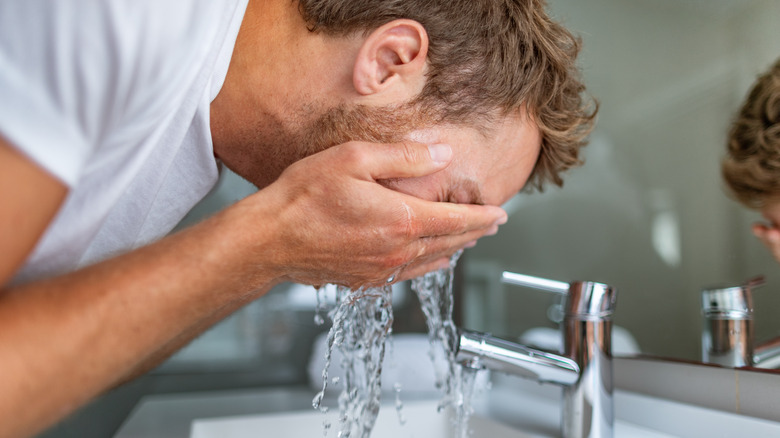 A man washes his face at home