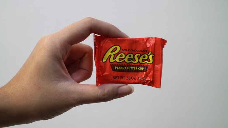 woman's hand holding Reese's peanut butter cup