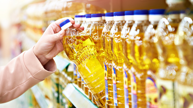 woman taking oil from a store shelf