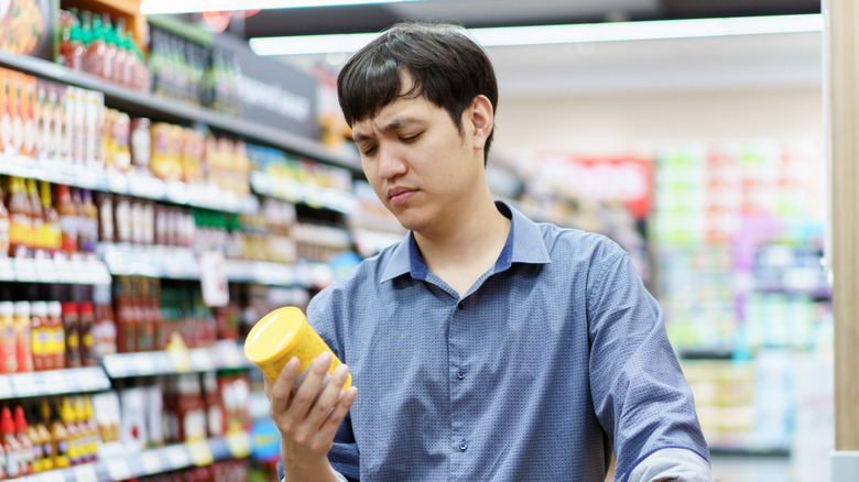 A man looking curiously at the ingredients on a food label