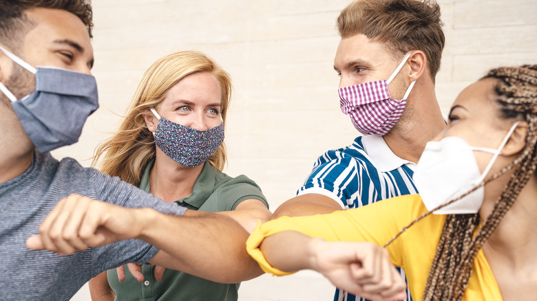 Group of people wearing masks bumping elbows