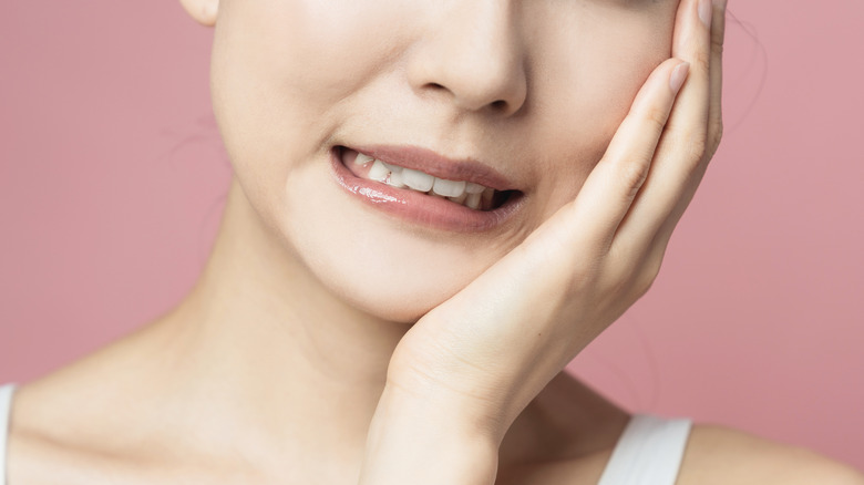 Woman with a canker sore in her mouth, holding face in pain