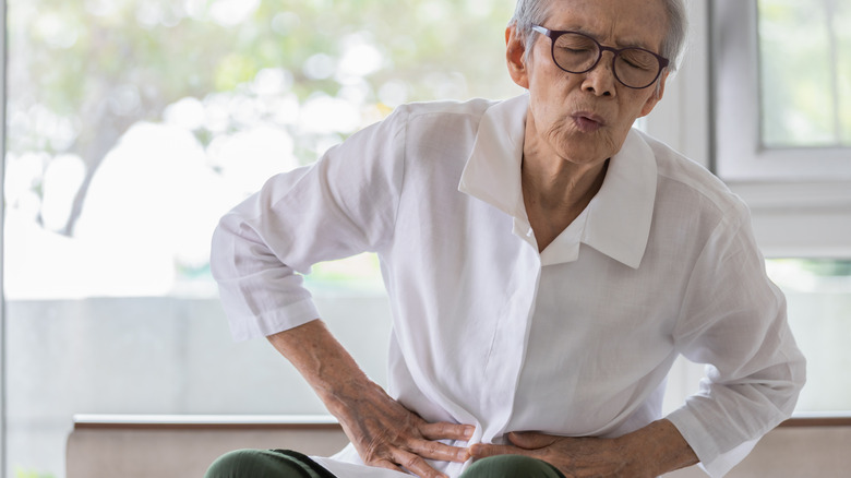 senior patient with gut disease holding stomach in pain