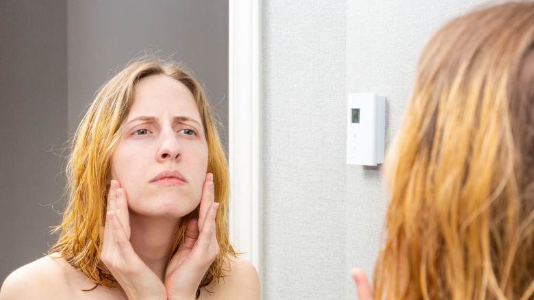 woman examines face in the mirror