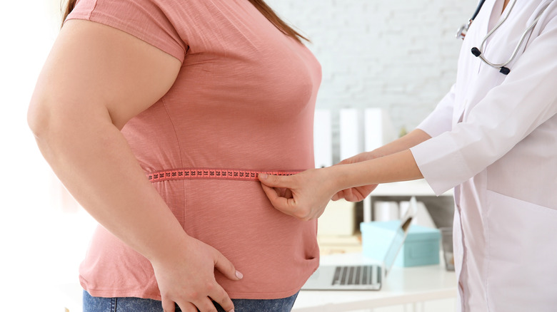 a doctor measuring a woman's belly fat