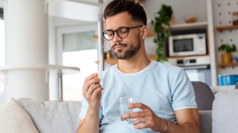 Man holding pill and glass of water