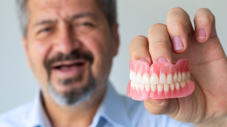 man holding his dentures