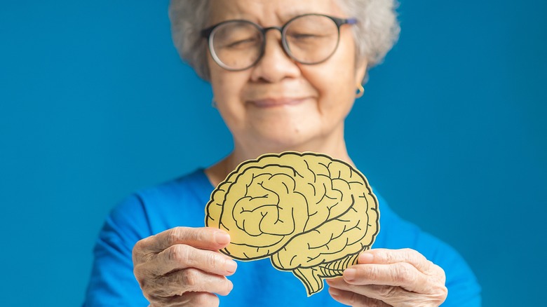 elderly woman holding brain cutout