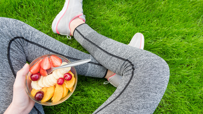 Woman eating fruit sitting on grass