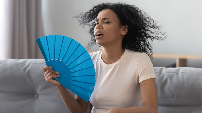 woman using fan to cool off