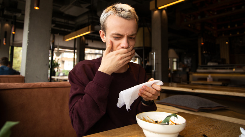 Person covering mouth at restaurant