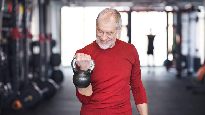 older man curling a kettlebell